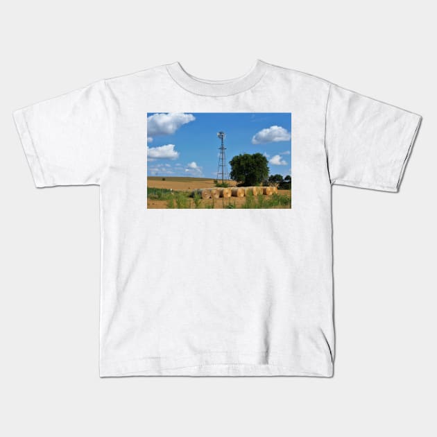 Kansas Windmill with Hay Bales and sky. Kids T-Shirt by ROBERTDBROZEK